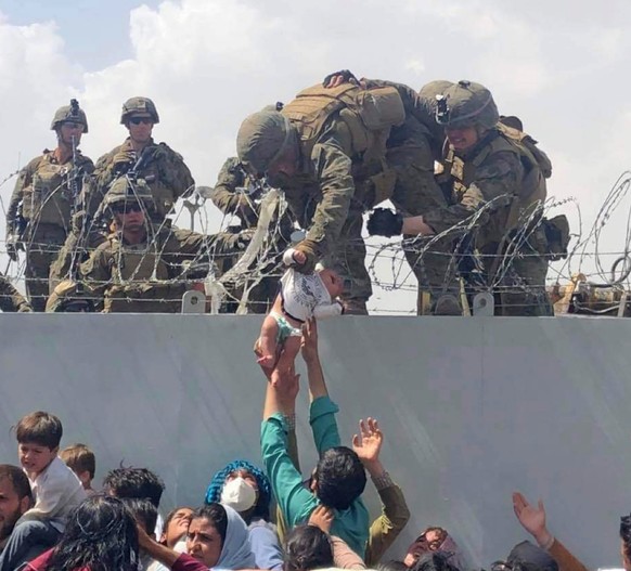 ARCHIV - 19.08.2021, Afghanistan, Kabul: Dieses von Omar Haidari zur Verf�gung gestellte Videostandbild zeigt ein Baby, das von US-Soldaten �ber eine Mauer am Flughafen von Kabul gehoben wird. Der S�u ...