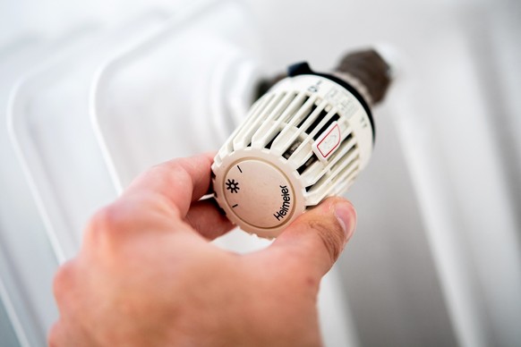 ARCHIV - 04.10.2021, Niedersachsen, Hannover: Ein Mann dreht in einer Wohnung am Thermostat einer Heizung. (zu dpa: "Viel Nachfrage zu Energiepreisen bei Verbraucherzentrale") Foto: Hauke-Ch ...