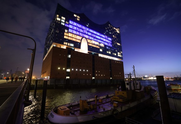 25.02.2022, Hamburg: Einige Fenster in der Fassade der Elbphilharmonie sind am Abend in den Farben der Ukraine beleuchtet. Angesichts des russischen Einmarschs in die Ukraine hat Hamburg seine Solidar ...