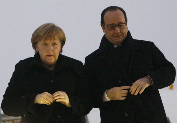 epa04614482 German Chancellor Angela Merkel (L) and French President Francois Hollande (R) button up their coats while walking downstairs after a meeting inside a plane at an airport near Minsk, Belar ...