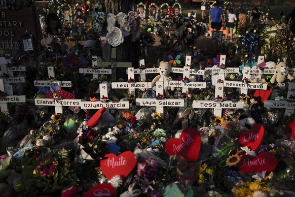 FILE - Flowers are piled around crosses with the names of the victims killed in a school shooting as people visit a memorial at Robb Elementary School to pay their respects May 31, 2022, in Uvalde, Te ...