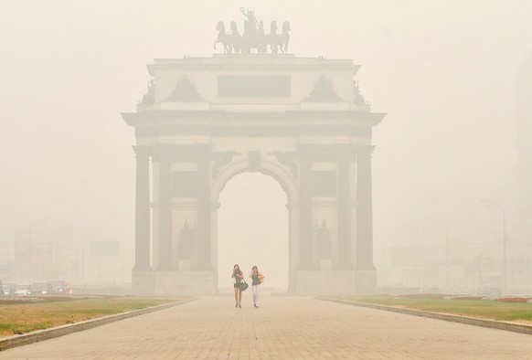ITAR-TASS: MOSCOW, RUSSIA. AUGUST 8, 2010. People walk near the Triumphal Arch. A thick blanket of smog from forest and peat fires continues to hang over the Russian capital, with temperatures averagi ...