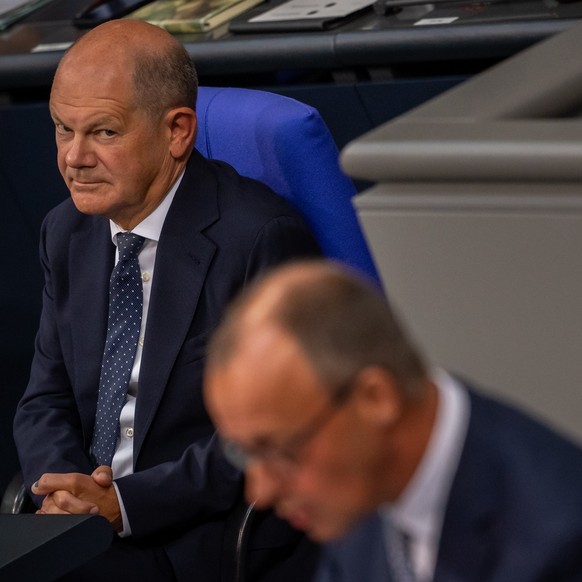 ARCHIV - 11.09.2024, Berlin: Bundeskanzler Olaf Scholz (SPD), schaut zu Friedrich Merz, CDU Bundesvorsitzender und CDU/CSU Fraktionsvorsitzender im Bundestag, in der Generaldebatte zum Bundeshaushalt  ...