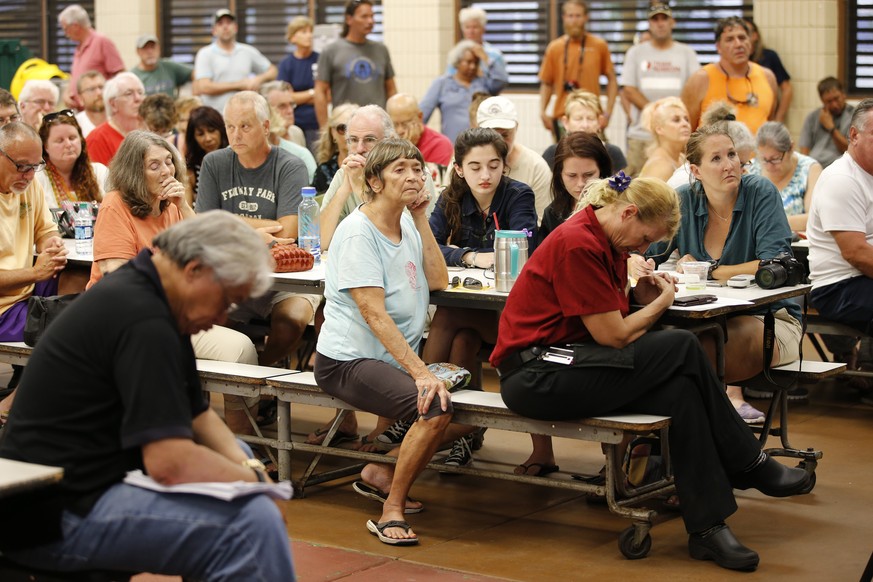 Residents from the lava affected areas of the Big Island hold a prayer before the start of a community meeting with local authorities at Pahoa High School, Friday, May 4, 2018, in Pahoa, Hawaii. (AP P ...