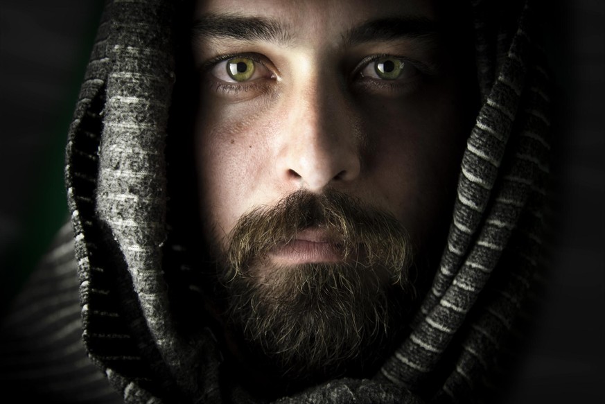 The dull look of the green-eyed bearded man with his head covered. Like a traveler living in the desert.
